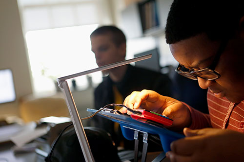 Estudiante masculino de secundaria utilizando un dispositivo de tecnología de asistencia en el aula
