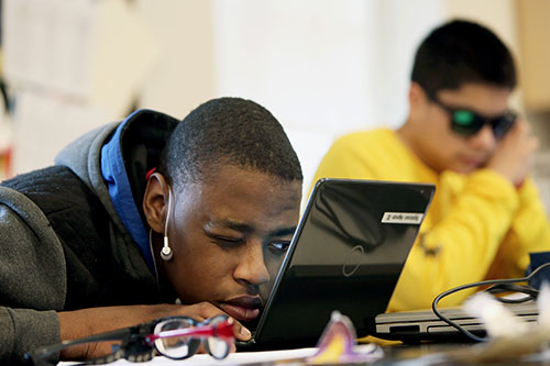 Estudiante masculino de secundaria mirando atentamente la pantalla del ordenador